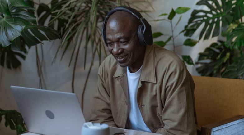 Older man smiles in front of laptop